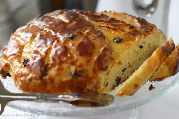 Ein goldbraun gebackenes Osterbrot mit Rosinen, glasiert und angeschnitten, bereit zum Genießen.