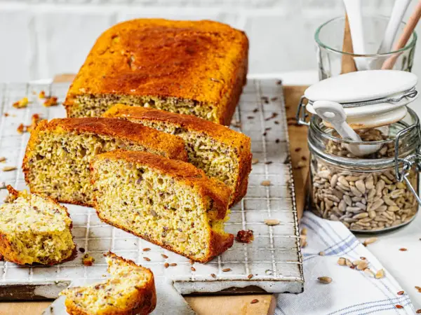 Ein saftiges low carb brot rezept mit Sonnenblumenkernen und Leinsamen, frisch aufgeschnitten auf einem Gitter.