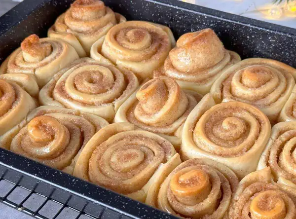 Frisch gebackene, gesunde Zimtschnecken in einer Backform. Sie duften nach Zimt und Zucker und sind bereit zum Genießen.