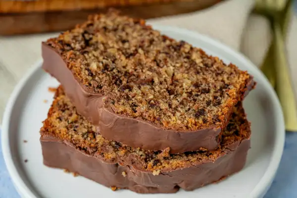 Zwei Scheiben saftiger Schoko Nuss Kuchen mit Schokoladenglasur auf einem Teller.