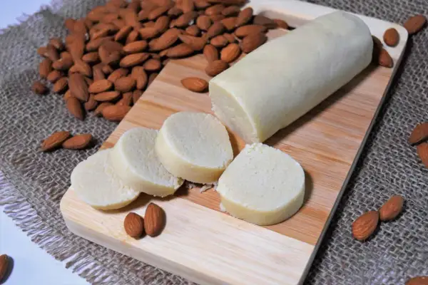 Frisch zubereitetes Marzipan, bereit zum **Marzipan selber machen**. Mandeln und Marzipanrolle auf Holzbrett.