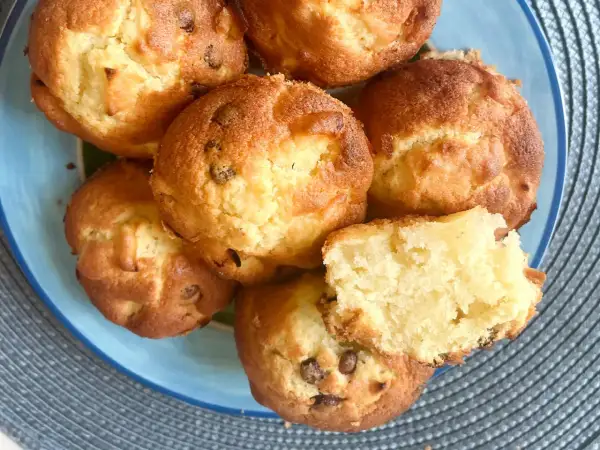 Saftige Apfelmus Muffins mit Schokostückchen auf einem blauen Teller. Einer ist aufgeschnitten und zeigt die lockere Textur.
