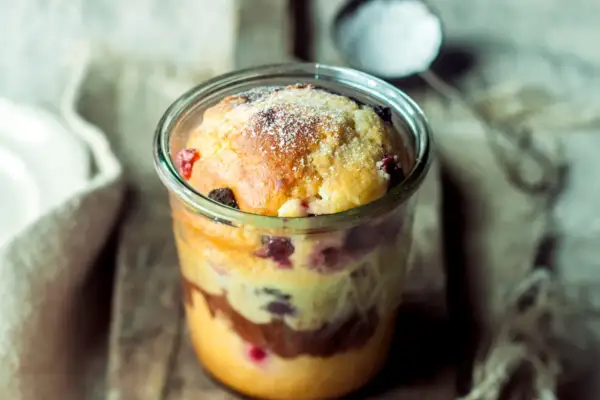 Saftiger Kuchen im Glas mit Beeren und Schokoschichten, bestäubt mit Puderzucker. Ein Genuss zum Löffeln!