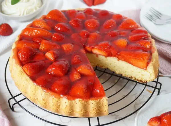 Eine saftige Erdbeer Torte mit frischen Früchten und glänzendem Tortenguss auf einem Gitterrost.