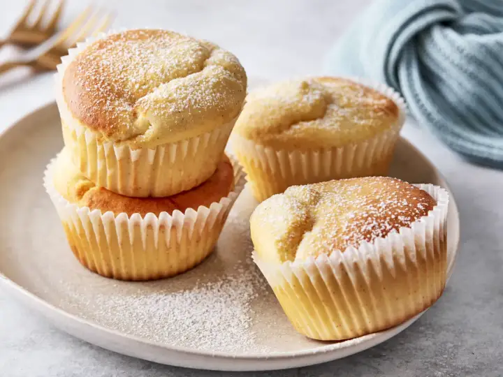 Saftige Muffins mit Quark, bestäubt mit Puderzucker, auf einem Teller arrangiert.